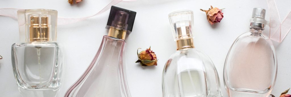close-up-of-various-perfume-bottles-and-dried-roses-1024x341