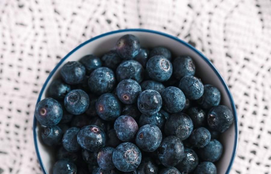 high-angle-shot-bowl-filled-with-blueberries-nice-white-tablecloth-table